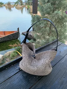 Detailed hollow crochet patterns on bohemian straw beach bag with dark leather strap