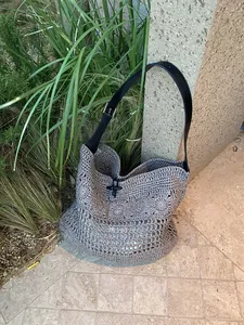 Detail of grey handmade woven beach bag with black leather strap and horn toggle closure
