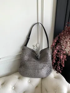Close-up of woven straw beach bag featuring a black leather strap and toggle closure