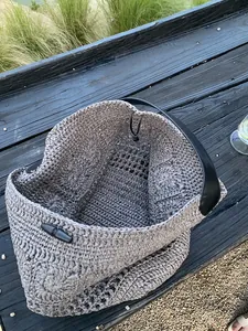 Close-up of hand-woven straw beach bag with hollow texture and leather toggle closure