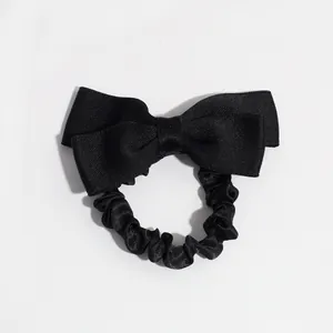 Elegant black bow hair tie featuring ribbed fabric and glossy satin finish