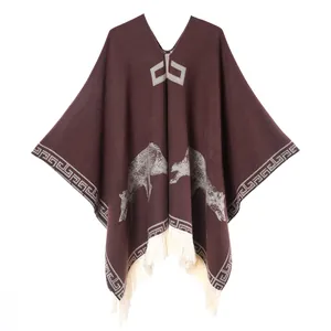 Detailed knit texture of a brown poncho with ethnic wolf pattern and white tassels