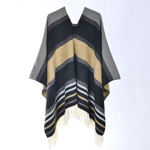 Detail of knitted poncho with retro geometric patterns and long cream fringe trim