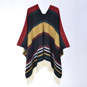 Detail of bohemian knit poncho featuring colorful geometric patterns and ivory tassels