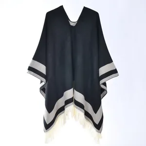 Detail of V-neck knitted poncho featuring gray stripes and cream tassel fringe