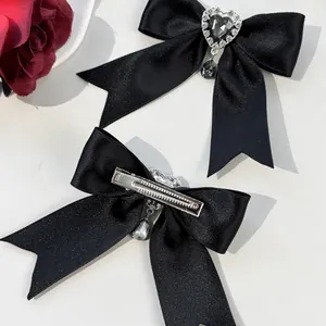 Detailed view of black satin bow hair clip with heart rhinestone and metal duckbill clip