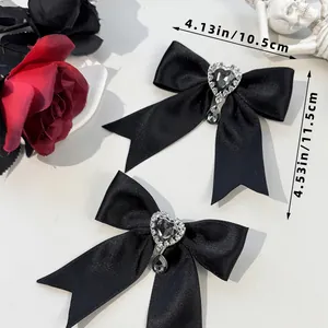 Detail of gothic black satin bow hair clips with heart gems and teardrop rhinestones