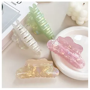 Close-up of four iridescent cloud hair claws in pastel shades on a white plate