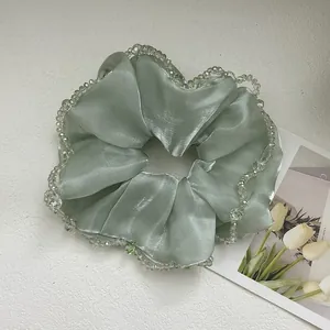 Detail of silk hair scrunchie in mint green with crystal beads and smooth texture