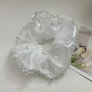 Close-up of white satin scrunchie with crystal beads and elegant silk texture