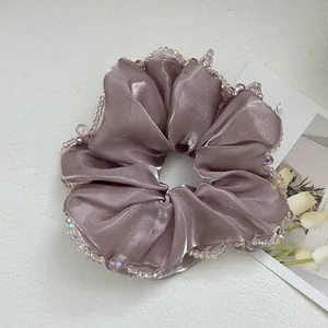 Detail of mauve satin scrunchie featuring shimmering fabric and iridescent crystal bead edges