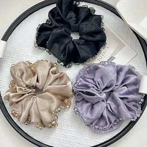 Close-up of satin hair scrunchies with crystal beads in black, gold, and purple
