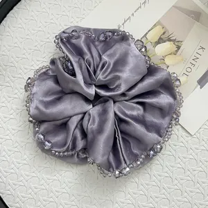 Macro detail of lilac satin scrunchie with beaded edges on a minimalist tray