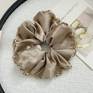 Macro detail of champagne gold satin scrunchie with brown crystal bead trim