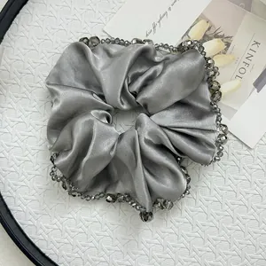 Macro detail of silver satin hair scrunchie with sparkling grey crystal bead trim