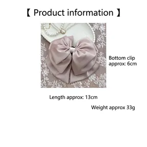 Detail of pink satin bow hair claw measuring 13cm with pearls and lace backdrop