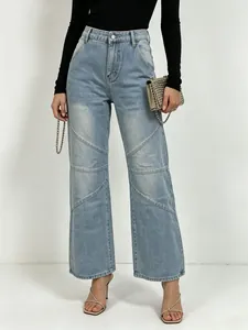 Detail of light blue high-waisted denim jeans featuring diagonal panelled stitching and washed finish