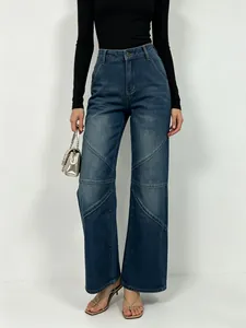 Detail of high waisted wide leg jeans featuring V-shaped patchwork stitching and deep blue wash