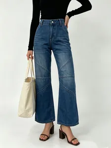 Detail of high waist denim jeans with geometric patchwork stitching and wide leg cut