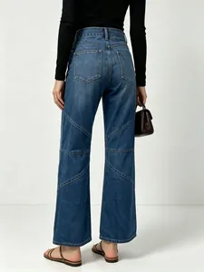 Detail of high-waist blue denim jeans with geometric patchwork stitching on back pockets