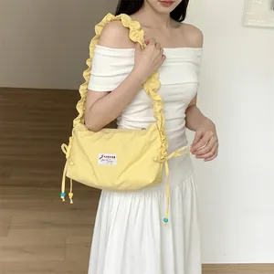 Close-up of pale yellow pleated canvas bag with adjustable drawstrings and blue beads
