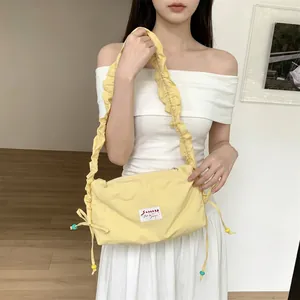 Detail of lemon yellow pleated canvas bag with ruffled shoulder strap and bead charms