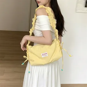 Detail of light yellow ruched canvas bag showing side drawstring and decorative beads