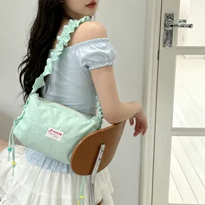 Detail of mint green pleated canvas bag with ruffle strap and drawstring bead accents