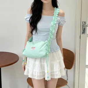 Detail view of mint green canvas bag featuring ruffled strap and colorful bead drawstring