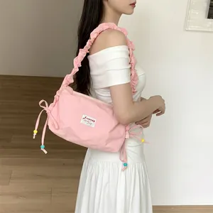 Close-up of pink pleated shoulder bag with drawstring bows and colorful beads