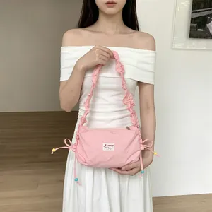 Detail of pink canvas shoulder bag featuring pleated strap and colorful beads