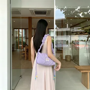 Detail of light purple pleated canvas bag with colorful beads and textured shoulder strap