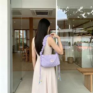 Detail of light purple pleated canvas shoulder bag with colorful beads and logo
