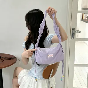Detail of lavender canvas bag with pleated strap and drawstring beads in lifestyle setting