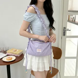 Close-up of lavender pleated shoulder bag with brand label and ruched strap detail