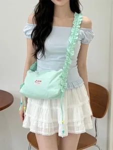 Mint green pleated canvas crossbody bag with adjustable strap worn by model