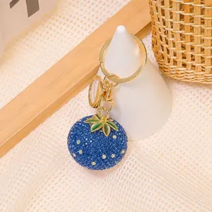 Vista dettagliata del portachiavi a forma di frutto blu con strass, foglia oro e anello