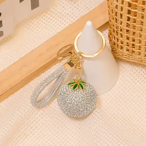 Dettaglio del portachiavi a forma di frutto con strass e finiture dorate su griglia