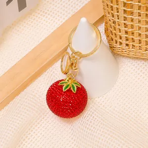 Dettaglio portachiavi a forma di pomodoro con strass rossi e anello in metallo dorato