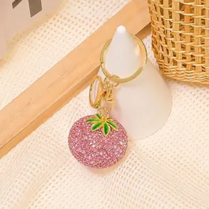 Dettaglio di portachiavi a forma di frutto con strass rosa e chiusura dorata