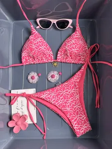 Close-up of pink floral bikini set with halter top, side-tie bottoms and gold flower charm