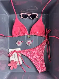 Detailed flat lay of pink halter bikini with daisy print bottom and floral metal buckle