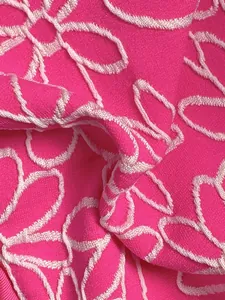 Close-up of pink bikini fabric featuring white floral embroidery and textured pattern