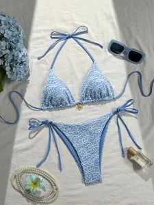 Sky blue bikini detail showing white floral embroidery and gold flower pendant