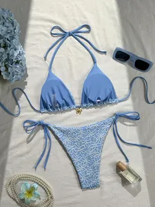 Detail of light blue bikini featuring white daisy embroidery and gold floral charm