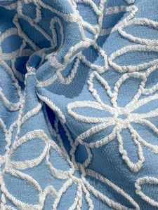 Macro shot of light blue textured jacquard fabric with white floral embroidery detail