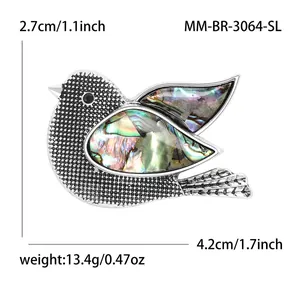 Elegant bird brooch in silver metal with colorful abalone shell wings and black stone eye