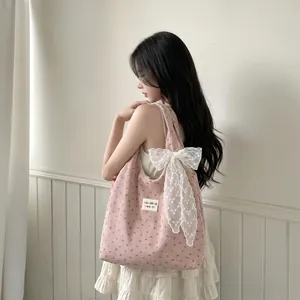 Gros plan détaillé d'un sac cabas en velours côtelé rose avec nœud en dentelle