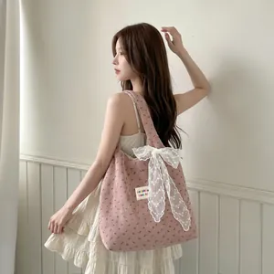 Détail du sac cabas en velours côtelé rose avec motif floral et nœud en dentelle blanche