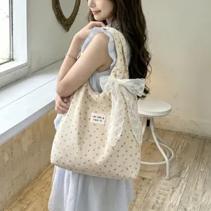 Détail du sac cabas en velours côtelé fleuri avec un grand nœud en dentelle blanche et étiquette
